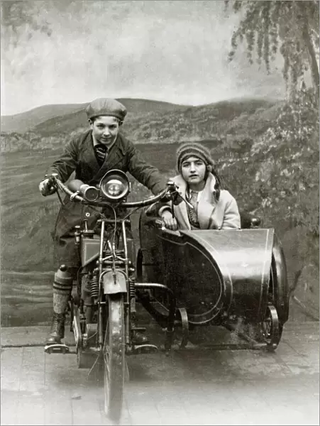 Boy & girl on a 1922 Royal Enfield motorcycle & sidecar in a