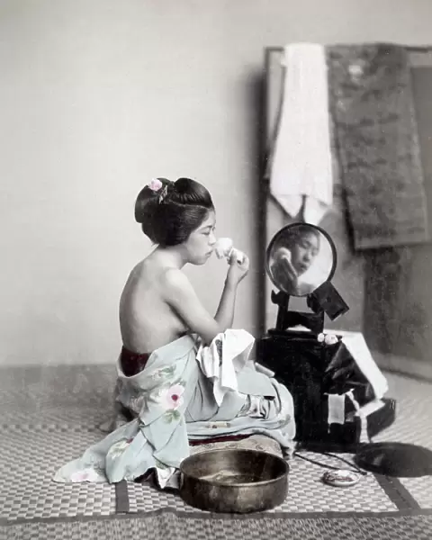 Young woman putting on makeup at a mirror, Japan, c. 1880 s