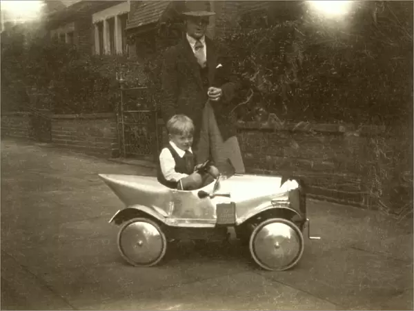 Small boy with chrome shiny silver pedal car