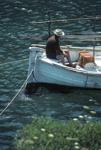 Boatman in stern of a small open fishing boat Menorca, Spain