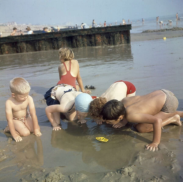 Children playing in a pool on a sandy beach