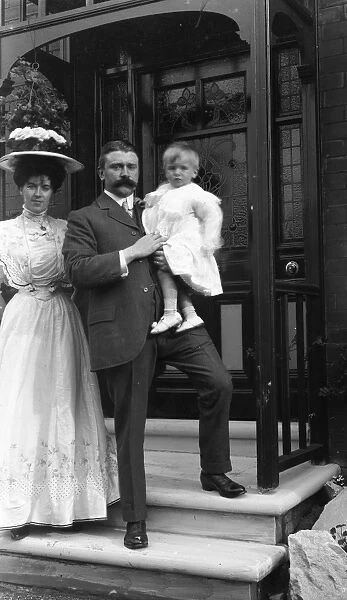 Elegant Edwardian couple with child outside house
