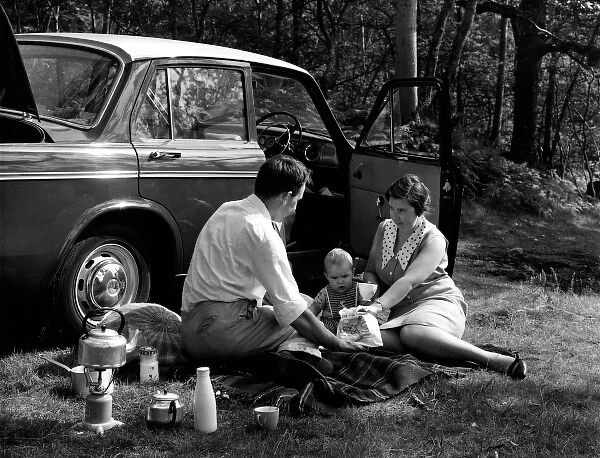 Family of three picnic by their car