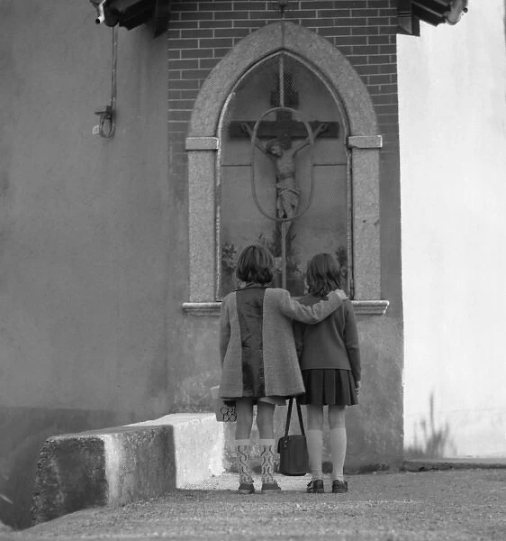 Two girls looking at a crucifix outside a church