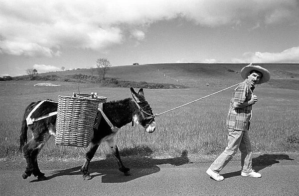 Hunter Davies leads a donkey along a road in rural France