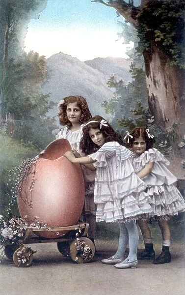 Three little girls with a large Easter egg on a trolley