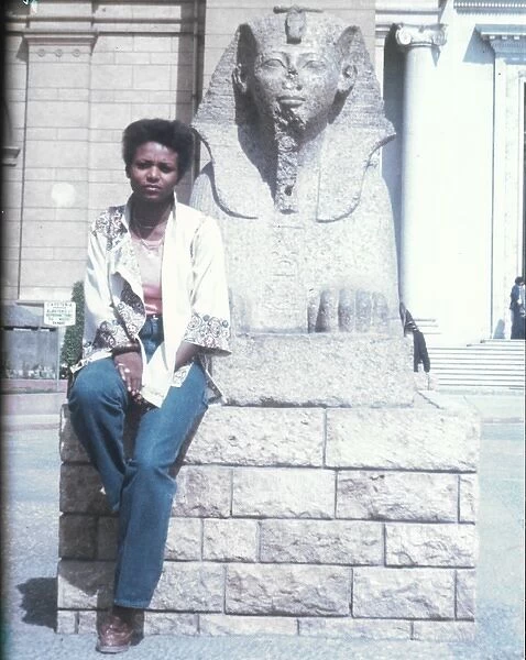 Lorna Holder sitting by a Sphinx-like statue - Egyptian Muse