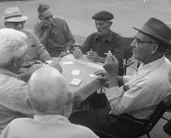Six men playing cards at a table in the street