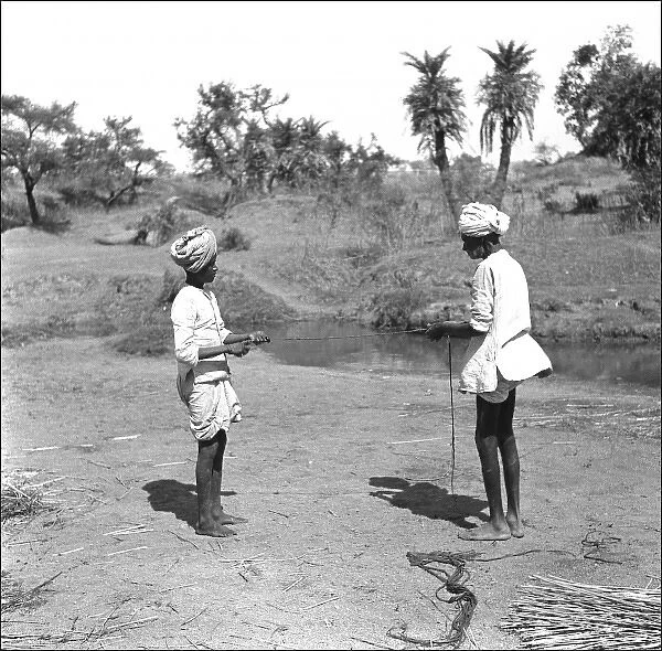 Two Men tie reeds by a stream