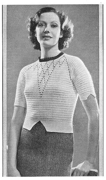 Model wearing a knitted sweater in white Tricoton cotton with shaped sleeve cuffs. Date: 1935