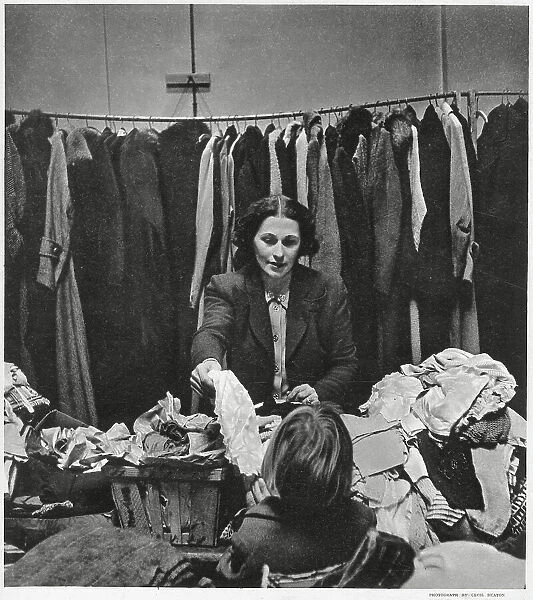 Mrs Robert Hudson wife of Minister of Agriculture and member of the Women's Voluntary Service, in East End, London. Giving out hundreds of articles of clothing and other comforts to homeless people who have lost their belongings