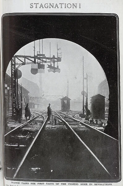 Photograph of rail strike in France, with soldier and striking worker with rifles and bayonets, on railway line by signals, at the exit from a tunnel. Captioned, Stagnation