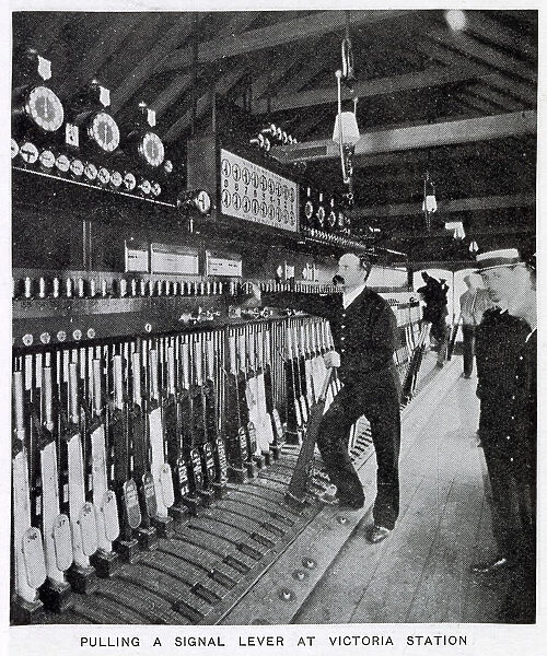 Photograph showing the signalman in the act of pulling a signal lever to allow a train to enter one of the platforms. Date: 1907