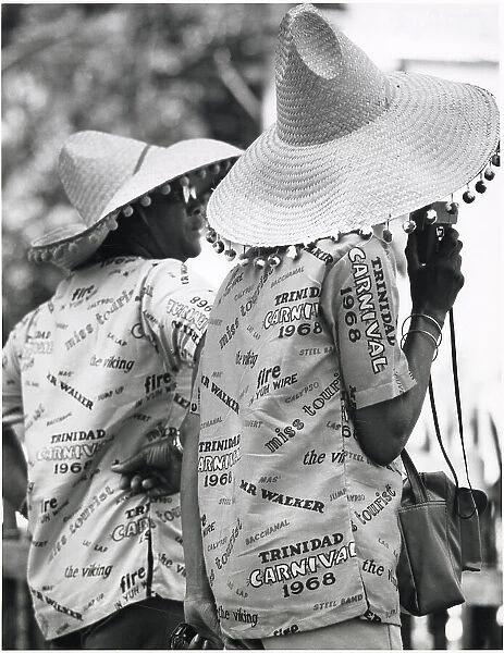Two revellers in matching party shirts and straw hats at the Port of Spain Carnival, Trinidad, West Indies. Date: 1968