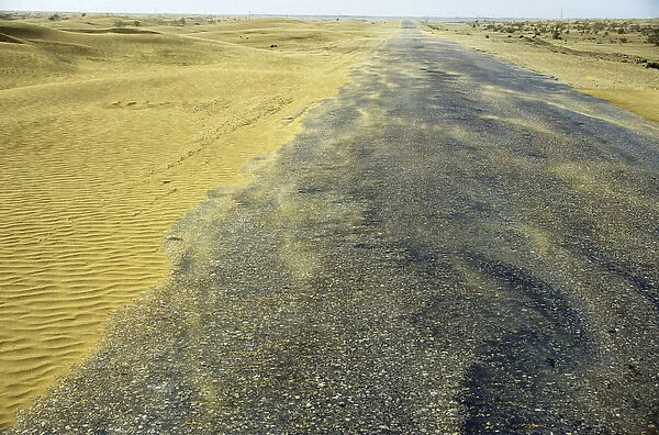 Sand dunes in a wind - Karakum desert encroach on a road