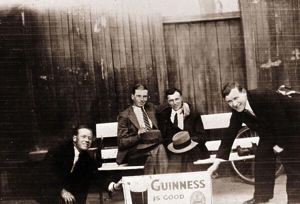 Four smiling men with Guinness advert