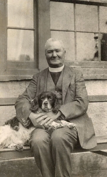Vicar with a spaniel dog on a bench