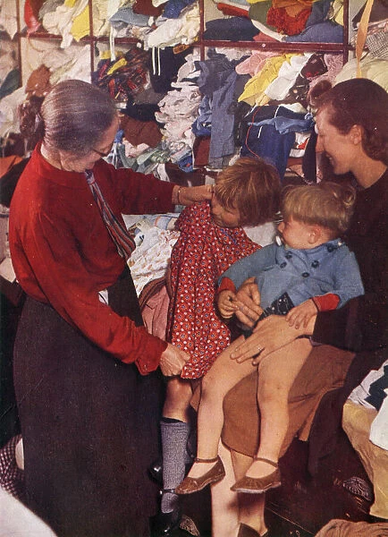 A W. V. S. worker selecting a frock for a little girl