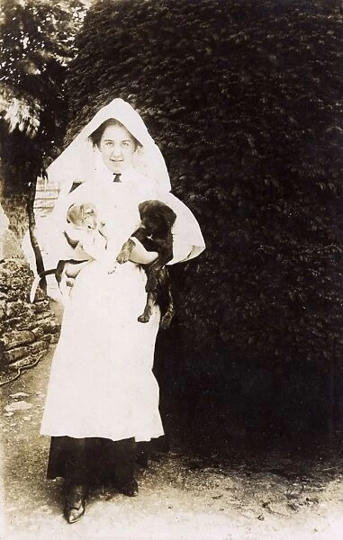 Woman holding two puppies in a garden