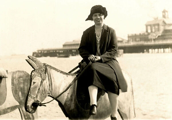 Woman perched on a wooden donkey at the seaside