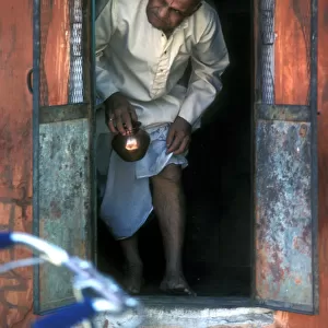 A bald man comes through a small door in a shrine in Jaipur