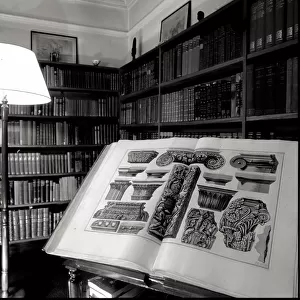 Bertrand Russell, 3rd Earl Russell (1872-1970), British philosopher and author -- a large book open at a page of architectural illustrations in the study of his home, Plas Penrhyn, Wales. Date: late 1960s