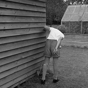 Boy with cigarette behind the garden shed