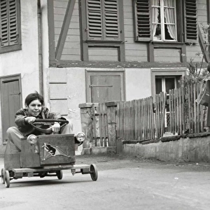 Boy on a go-kart passing three adults