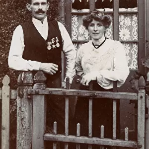 Couple at gate, man wearing Boer War medals