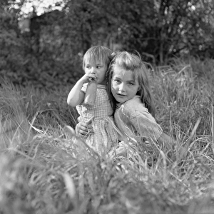 Two gipsy girls in a field, one with a feeding bottle