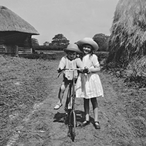 Girl and toddler riding a bicycle in a field