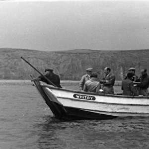 Group of men in a fishing boat with film camera
