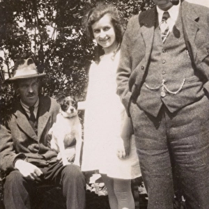 Three people and a dog in a garden