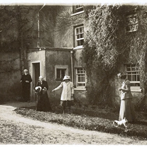 People and dog outside a large house