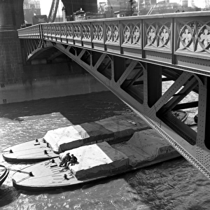 River barges and dockworkers towed under Tower Bridge, Londo