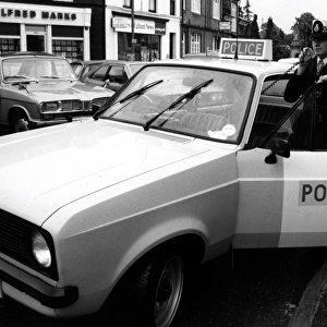 Woman police officer with car and radio, Egham, Surrey