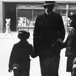 Woman police officer holding hands with children, London