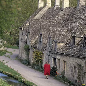 A woman walks past stone cottages in the village of Bilbury