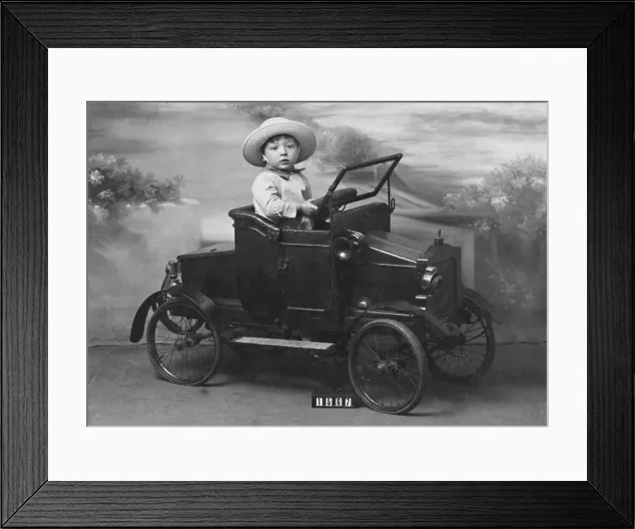 Framed Print : Little boy in toy car in studio portrait Framed Print : Little boy in toy car in studio portrait
