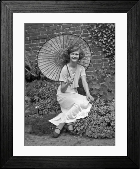 Framed Print : Young woman in a garden with a parasol