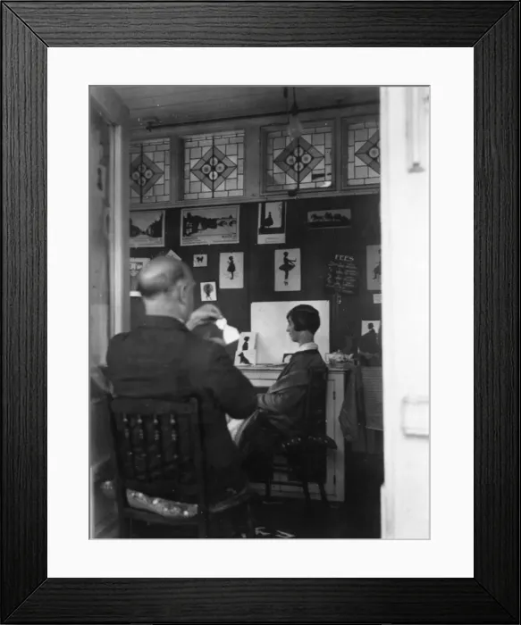 Framed Print : H. L. Oakley cutting a silhouette in his studio Framed Print : H. L. Oakley cutting a silhouette in his studio