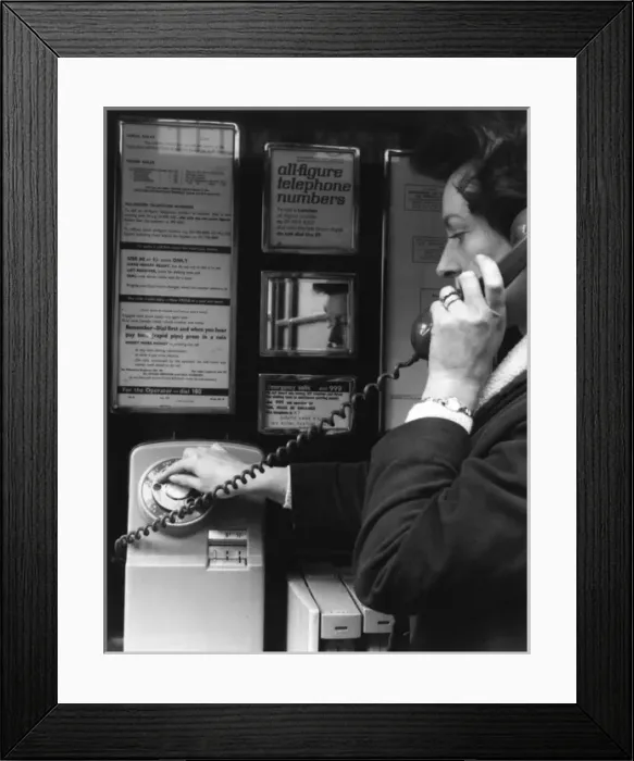 Framed Print : Woman dialling 999 in a public telephone box, London Framed Print : Woman dialling 999 in a public telephone box, London