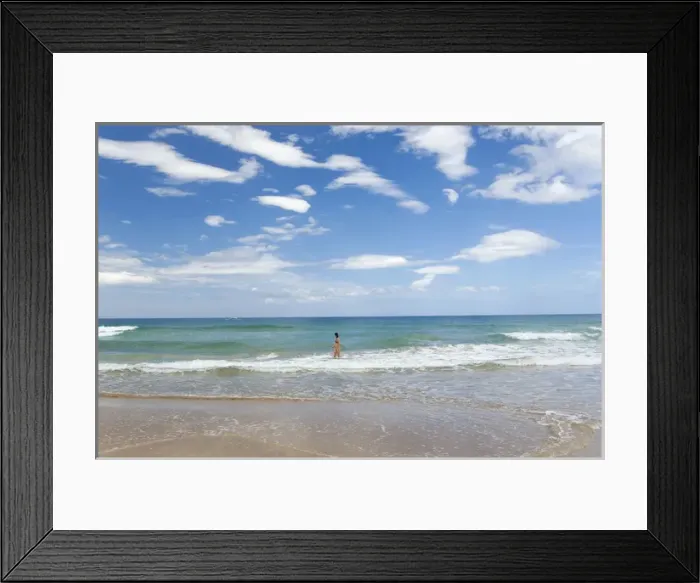 Framed Print : A girl baths and watches a passing boat on a beach Framed Print : A girl baths and watches a passing boat on a beach
