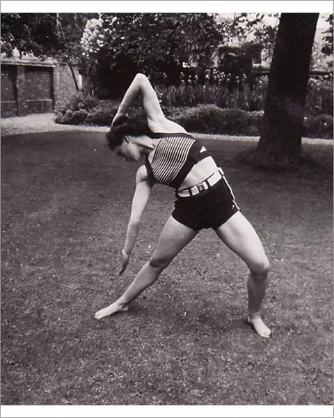 Female in shorts and striped top stretching on lawn