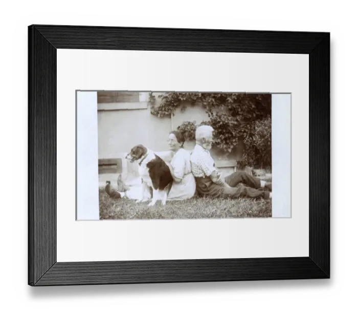 Framed Print : Couple sitting back to back in a garden, with dog