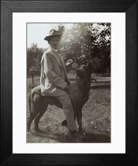 Framed Print : Young woman on dog statue in a garden Framed Print : Young woman on dog statue in a garden