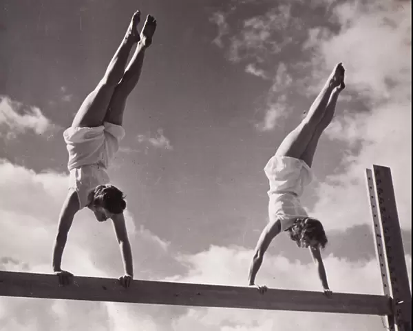 Two females handstands on beam
