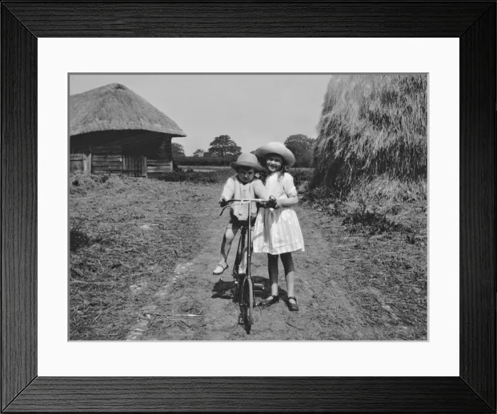 Framed Print : Girl and toddler riding a bicycle in a field Framed Print : Girl and toddler riding a bicycle in a field