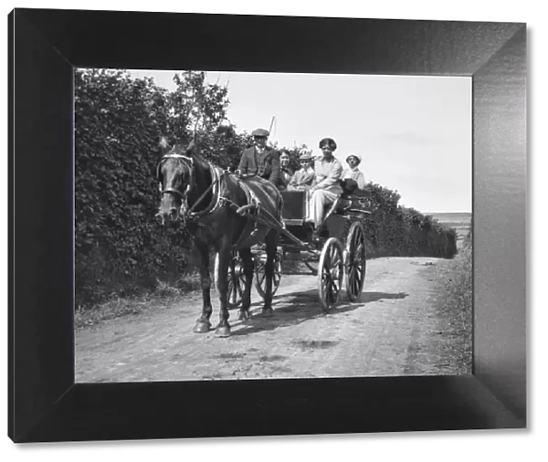 People on a horse-drawn cart on a country lane
