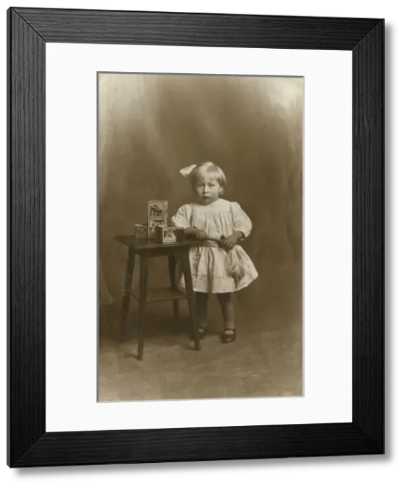 Framed Print : Studio portrait, little girl with table and toy bricks Framed Print : Studio portrait, little girl with table and toy bricks